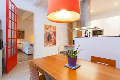 a kitchen with a wooden table and a red door at Bonito apartamento en La Rambla del Poblenou in Barcelona