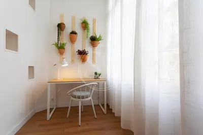 a desk with potted plants on a wall with a chair at Cómodo piso en Eixample in Barcelona
