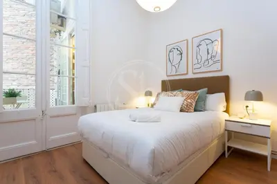 a white bedroom with a large bed and a window at Cómodo piso en Eixample in Barcelona