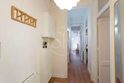 a hallway with white walls and wood floors and a light fixture at Cómodo piso en Eixample in Barcelona