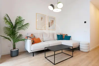 a living room with a white couch and a tv at Moderno apartamento familiar en Eixample in Barcelona
