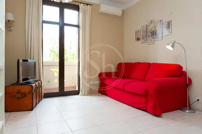 a red couch in a living room with a tv at Apartamento céntrico para 4 in Barcelona