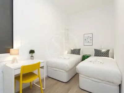 a white kitchen with a table and a clock at Wonderful apartment for 6 in Barcelona