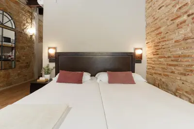 a bedroom with a large white bed with a brick wall at AinB Picasso-Corders Apartments in Barcelona