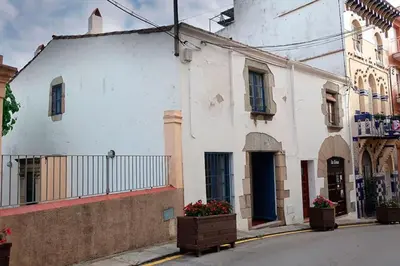 a white building with flowers on the side of a street at Charming house in Sant Pol facing the sea in San Pol de Mar