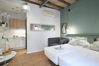 a bedroom with a large white bed and a kitchen at AinB Gothic-Jaume I Apartments in Barcelona