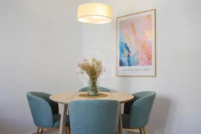 a dining room table with chairs and a vase with flowers at Luminescent Valencia Apartment in Barcelona