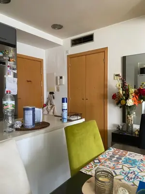 a kitchen with a counter and a table with a green chair at Piso cómodo Habitación in Sabadell