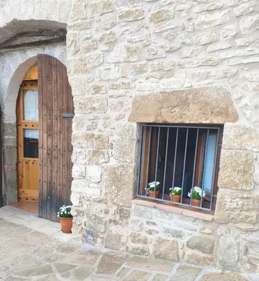 a stone building with a window and a wooden door at La Julita in San Quírico Safaja