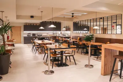 an empty restaurant with wooden tables and chairs at Aerohotel Barcelona Airport 24h in El Prat de Llobregat