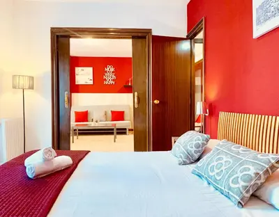 a bedroom with a bed with a red wall at La Pedrera Residence in Barcelona