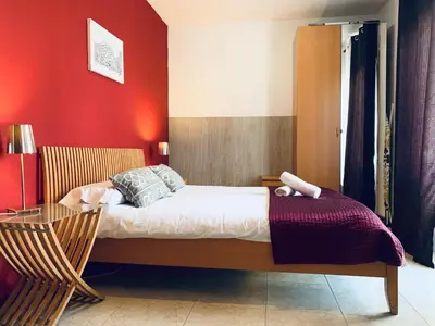 a bedroom with a bed with a red wall at La Pedrera Residence in Barcelona