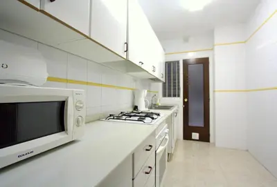 a white kitchen with a microwave and a stove at La Pedrera Residence in Barcelona
