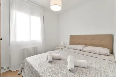 a white bedroom with a bed with towels on it at Sea View Penthouse in Vilanova i la Geltrú