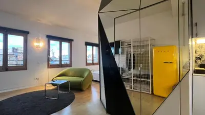 a living room with a green chair and a glass wall at Atico Central con Terraza in Barcelona
