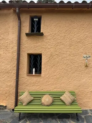 a green bench in front of a building with a window at Casa Rural CAL PAGÉS Montseny in Montseny