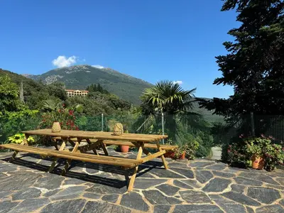 a picnic table and bench with a mountain in the background at Casa Rural CAL PAGÉS Montseny in Montseny