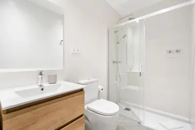 a white bathroom with a shower and a toilet at Fira Building in Hospitalet de Llobregat