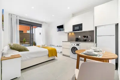 a white bedroom with a bed and a table at Fira Building in Hospitalet de Llobregat