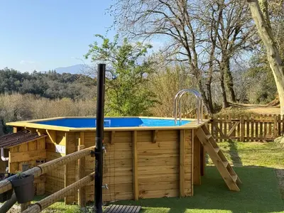a hot tub in a wooden deck with a pool at Casa Rural Can Ricós - El Mirador del Montseny in Vallgorguina