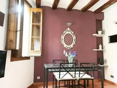 a dining room with a table and chairs against a burgundy wall at Luminoso apartamento 1 habitación cerca de Las Ramblas, hasta 4 pers, cocina equipada. - ES-341-6 in Barcelona