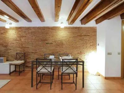 a dining room with chairs and a brick wall at Apartamento Céntrico en Edificio Histórico con Encanto para Familias, Hasta 5 Personas - ES-341-1 in Barcelona