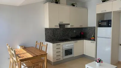 a kitchen with white cabinets and a wooden table and a table and chairs at SE Céntrico con Terraza in Terrassa