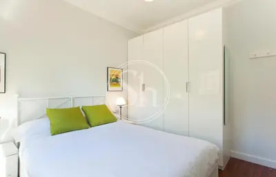 a white bedroom with a white bed with green pillows at Bonito apartamento 3 in Barcelona