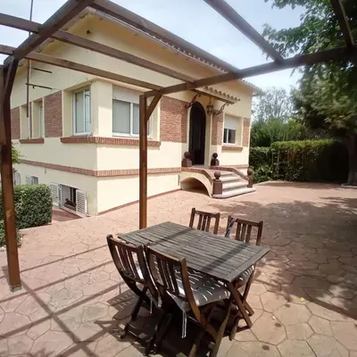 a wooden table and chairs in front of a house at Esplendida casa en Valldoreix in Sant Cugat del Vallès