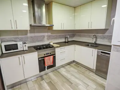 a kitchen with white cabinets and a stove and a sink at Bambino apartment by Hello Homes Sitges in Sitges