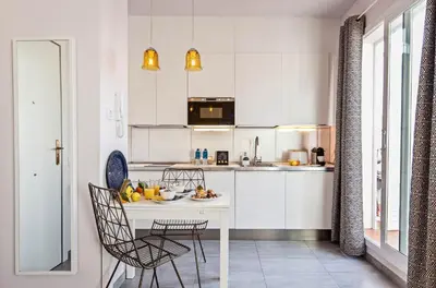 a kitchen with white cabinets and a table and chairs at Sweett - Atic Gracia in Barcelona