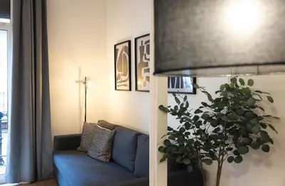 a living room with a blue couch and a plant at Stay U-nique Apartment Astúries in Barcelona