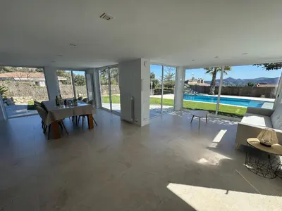 a living room with a table and chairs and a pool at CASA CON JARDIN, SAUNA, PISCINA PRIVADA y NATURALEZA CERCA DE BARCELONA in Pallejá