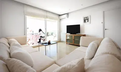 a living room with a large couch and a tv at Sitges Apartamente frente al mar con piscina in Sitges