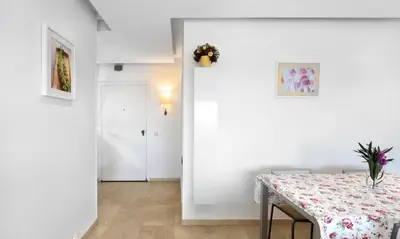 a dining room with a table and a white wall at Sitges Apartamente frente al mar con piscina in Sitges