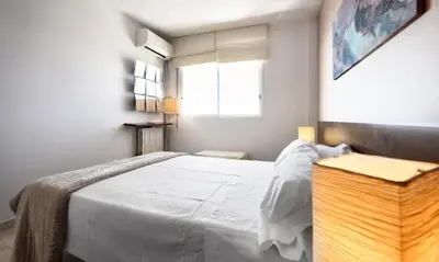 a bedroom with a large white bed and a window at Sitges Apartamente frente al mar con piscina in Sitges