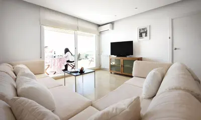 a living room with a large couch and a tv at Sitges Apartamente frente al mar con piscina in Sitges