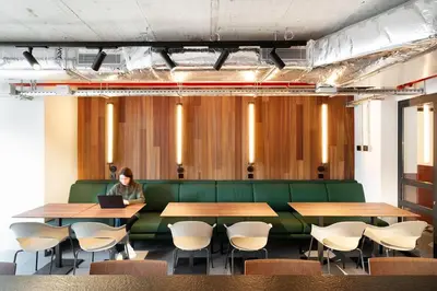 a woman sitting on a green couch in a conference room with a laptop at Residencia & Coliving para Postgrads in Barcelona