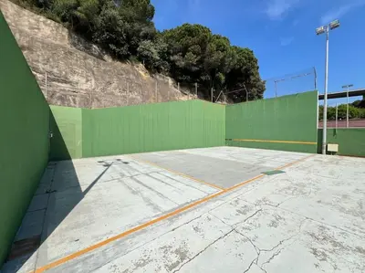 an empty tennis court with a green wall at Apartamento Montebello in Sant Vicenç de Montalt