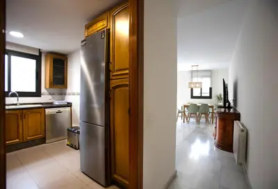 a kitchen with a stainless steel refrigerator and a dining room at Casa tonet in Badalona