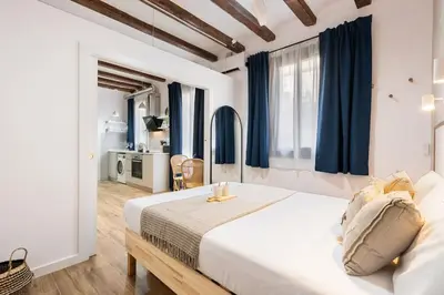 a bedroom with a large bed with blue curtains at Lodging Apartments Almirall Beach 32 in Barcelona