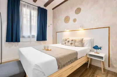 a bedroom with a large white bed with blue curtains at Lodging Apartments Almirall Beach 32 in Barcelona