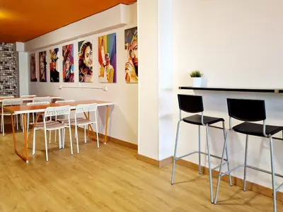 a room with tables and chairs and paintings on the wall at Arc House Barcelona in Barcelona