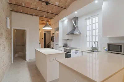 a kitchen with white counters and a brick wall at GuestReady - Una estancia encantadora en Sarrià-Sant Gervasi in Barcelona