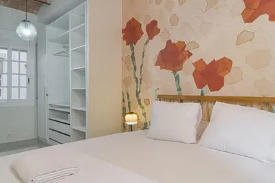 a bedroom with a white bed with red flowers on the wall at GuestReady - Una estancia encantadora en Sarrià-Sant Gervasi in Barcelona