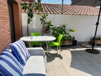 a patio with a white table and green chairs at Tranquilo y con terraza in Terrassa