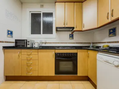 a kitchen with wooden cabinets and a stove top oven at GuestReady - Comfortable Retreat next to the beach in Barcelona