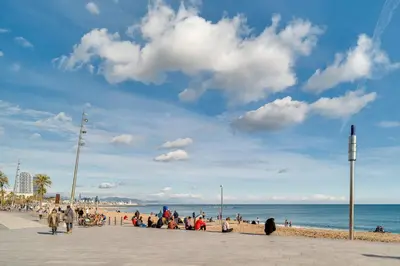 a group of people sitting on a beach near the ocean at GuestReady - Precioso refugio en la Barceloneta in Barcelona
