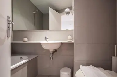 a bathroom with a sink and a toilet and a mirror at Flateli Llúria in Barcelona