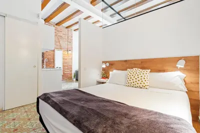 a bedroom with a large white bed with a wooden headboard at Flateli Borrell in Barcelona